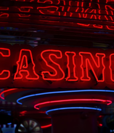 Neon lights display the word 'CASINO' in bright red, standing out against a dark background. The vibrant glow reflects a lively and bustling atmosphere.